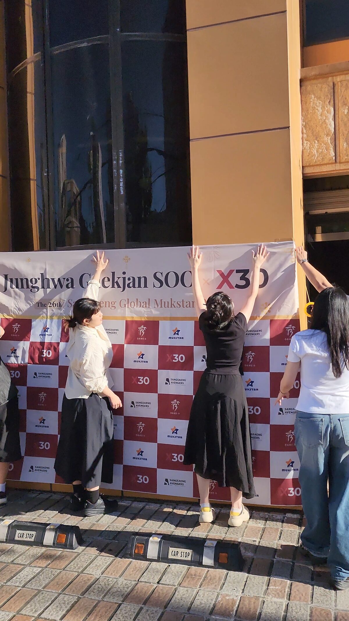 X30 and Mukstar Party staff setting up the event photo wall outside Junghwagaekjansu